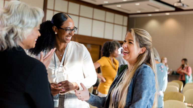 Group of three women talking and laughing together at a professional event