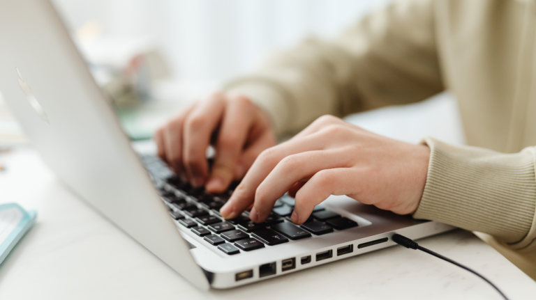 Close up of person's hands as they type on a laptop